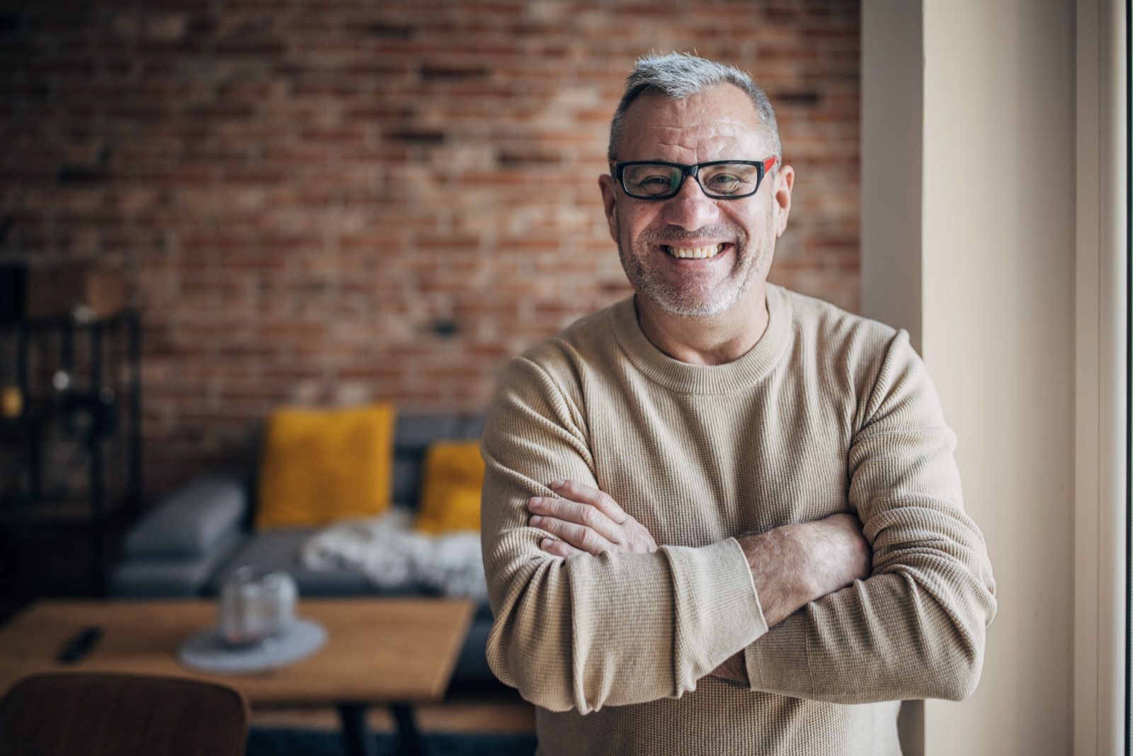 Smiling man with glasses in front of a brick wall